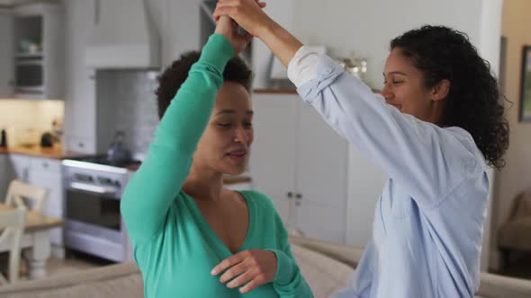 Romantic mixed race lesbian couple dancing in sitting room