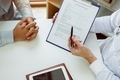 Confident female doctor reviews patient medical information and pointing to medical forms. - PhotoDune Item for Sale