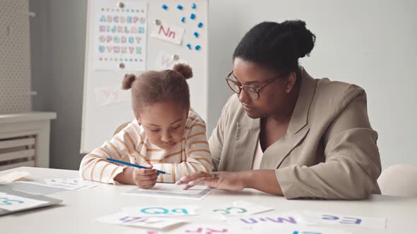 Preschool Girl Studying with Teacher in Classroom