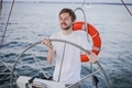 Happy young man steering wheel and looking far away on yacht on the sea. Sailing - PhotoDune Item for Sale