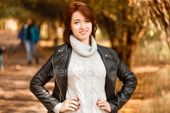 ay sweater and leather jacket. Girl enjoys autumn weather in forest, in autumn park. Girl autumn fashion clothes. I feel comfortable. Beauty style.