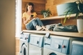 Woman with phone waits while clothes are washed in the laundry. - PhotoDune Item for Sale
