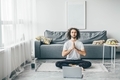 Man doing an online yoga class in his living room with laptop.  - PhotoDune Item for Sale