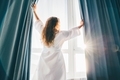 Woman opening curtains in room at sunrise. - PhotoDune Item for Sale