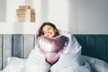 Woman sitting on bed with heart shaped balloons.  - PhotoDune Item for Sale