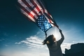 Happy woman holding united states flag against blue sky, independence day concept.  - PhotoDune Item for Sale
