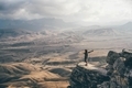 Woman standing on rock high in mountains and watches landscape of hills.  - PhotoDune Item for Sale