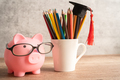 Pigging bank wearing eyeglass with colorful pencils; saving bank education concept. - PhotoDune Item for Sale