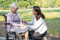 Caregiver help and care Asian senior woman patient sitting and happy on wheelchair in park. - PhotoDune Item for Sale