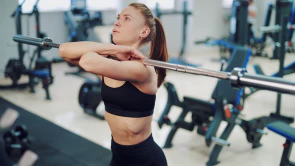 Young Woman with a Tail Performs Squats with a Barbell in the Gym 