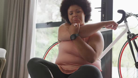 Video of midsection of plus size african american woman in sport clothes stretching at home