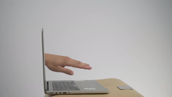 The Abstract Image of the Hackers Hand Reach Through a Laptop Screen for Stealing Credit Card in a