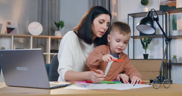 Woman Which Holding Small Attantive Son on Knees and Helping him