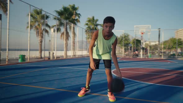 Young Caucasian Boy Basketball Player Dribbling and Practicing Ball Handling Skill on Court