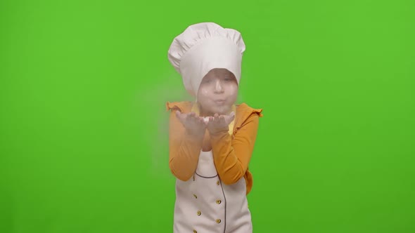 Child Girl Kid Dressed As Professional Cook Chef Blowing Flour From Hands Into Camera on Chroma Key