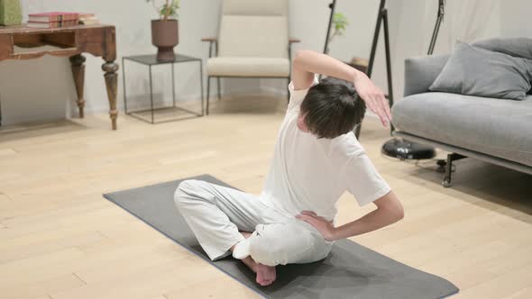 Young Asian Man Doing Stretches on Yoga Mat at Home