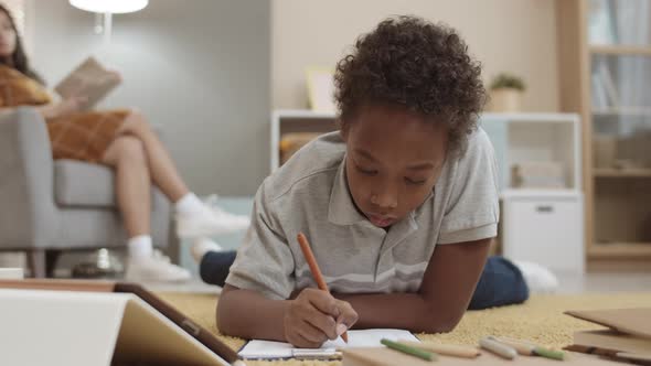 African Kid Doing Homework on Floor