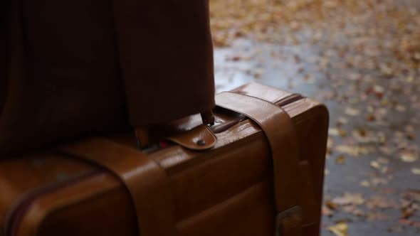 Stylish woman in coat with suitcase walking down the street