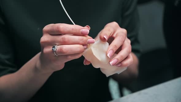 A woman occupied with hand made candles production, preparing a mold for wax. Slow motion