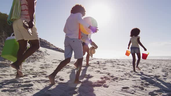 African american parents and their children walking with beach equipment on the beach