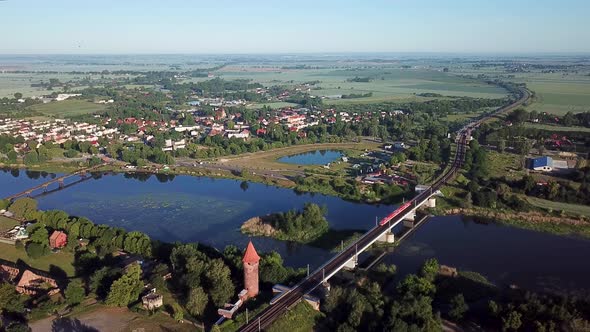 Aerial:The train is moving along the railway bridge at dawn