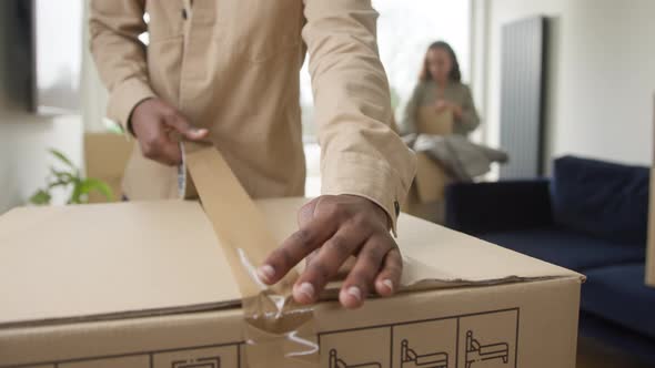 Young Couple In Lounge At Home Packing Removal Boxes Ready For House Move