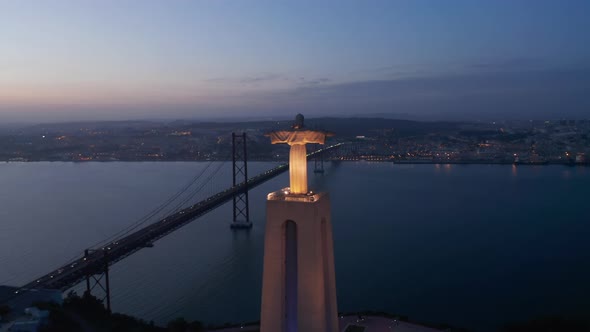 Aerial View of Illuminated Big Jesus Statue Above River Spanned By Cablestayed Bridge