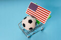 Soccer ball with USA flag in shopping cart on blue background. Football cup earnings. - PhotoDune Item for Sale