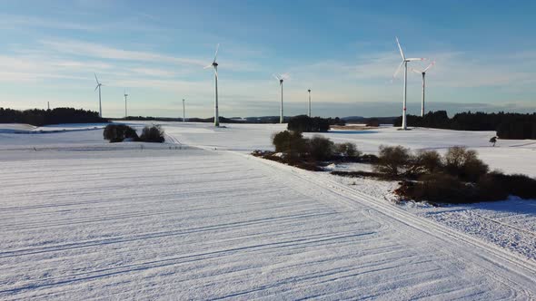 Snowy farmland with a windfarm in the distance. Aerial shot of a windfarm on a snowy field.