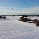 Snowy farmland with a windfarm in the distance. Aerial shot of a windfarm on a snowy field. - VideoHive Item for Sale