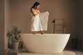 Rare view of attractive asian slim woman in towel staning in  white ceramic bathtub to refresh - PhotoDune Item for Sale