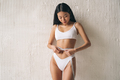 Asian woman in white bikini measuring waist line with tape measure - PhotoDune Item for Sale