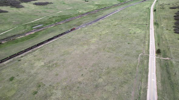 Aerial push in towards train transporting coal through midwest farmland, USA.