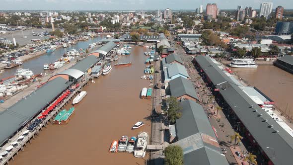 Aerial establishing shot of people visiting Puerto de Frutos in Tigre city, Argentina