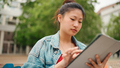Attractive Asian student girl wearing denim jacket using her tablet pc for study - PhotoDune Item for Sale