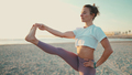 Beautiful woman in sportswear keeping balance looking confident during yoga practice by the sea - PhotoDune Item for Sale