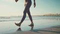 Close up shot of young woman wearing leggings walking along the sea. Close up female legs on beach - PhotoDune Item for Sale