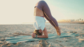 Beautiful yogi girl standing on her head doing yoga poses by the sea - PhotoDune Item for Sale
