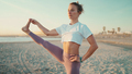 Portrait of beautiful woman in sportswear keeping balance during yoga practice by the sea - PhotoDune Item for Sale