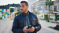 Portrait of confident man using smartphone standing on the evening city street - PhotoDune Item for Sale