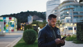 Young man wearing leather jacket checking his smartphone on the street - PhotoDune Item for Sale