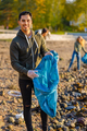 Young man collects garbage in bag with group of volunteers on sunny day - PhotoDune Item for Sale