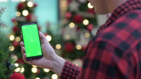 Rear View Of Young Hipster Man Using Phone Against Christmas Trees Outdoors