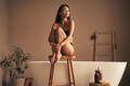Asian woman going to take morning bath, sitting on stool near bathtub in luxury bathroom - PhotoDune Item for Sale