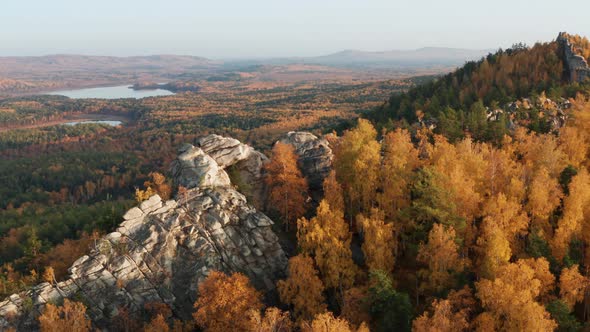 Aerial View of a Cliff Surrounded By a Colorful Autumn Forest at Sunset