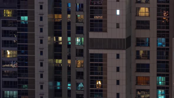 Apartment Windows of a Glazed Skyscraper Glow at Night with City Lights Reflection Aerial Timelapse