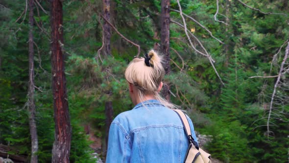 young tourist walks through mountainous area and looks at beautiful landscape.