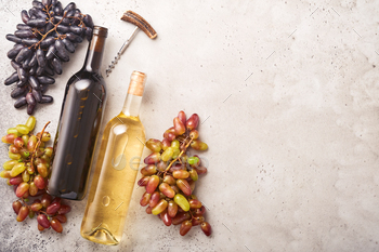 Two Wine bottles with grapes and wineglasses on old gray concrete table background with copy space. 