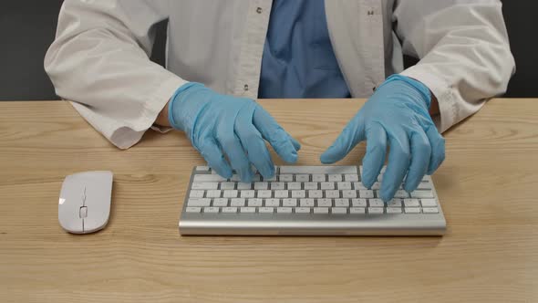 A Man in Blue Protective Gloves and a White Coat Uses a Computer Keyboard. Sanitation Process and