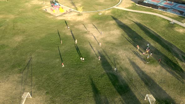 Kids playing kickball in the park - aerial orbiting view